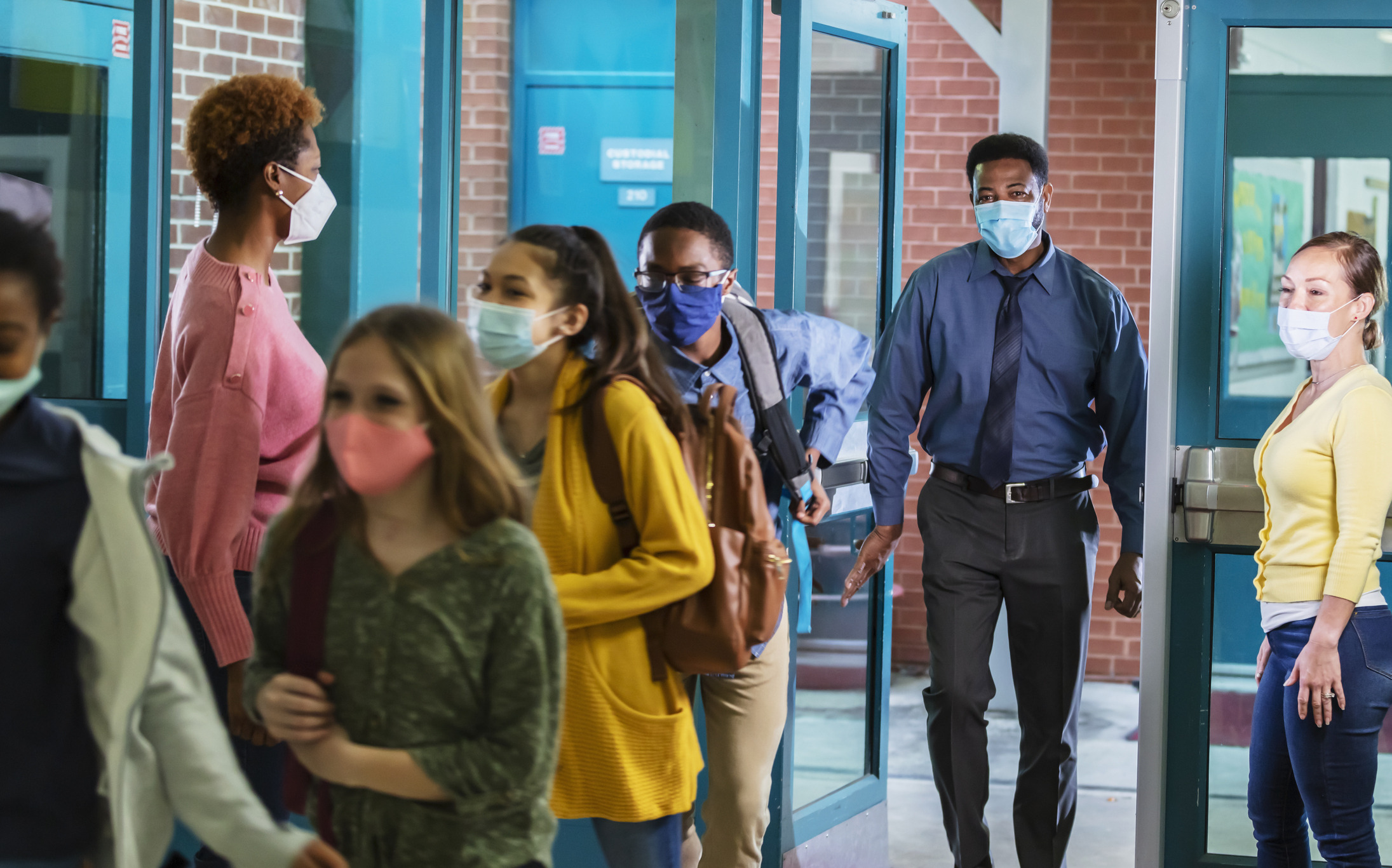 Parents drop middle school students off, with face masks