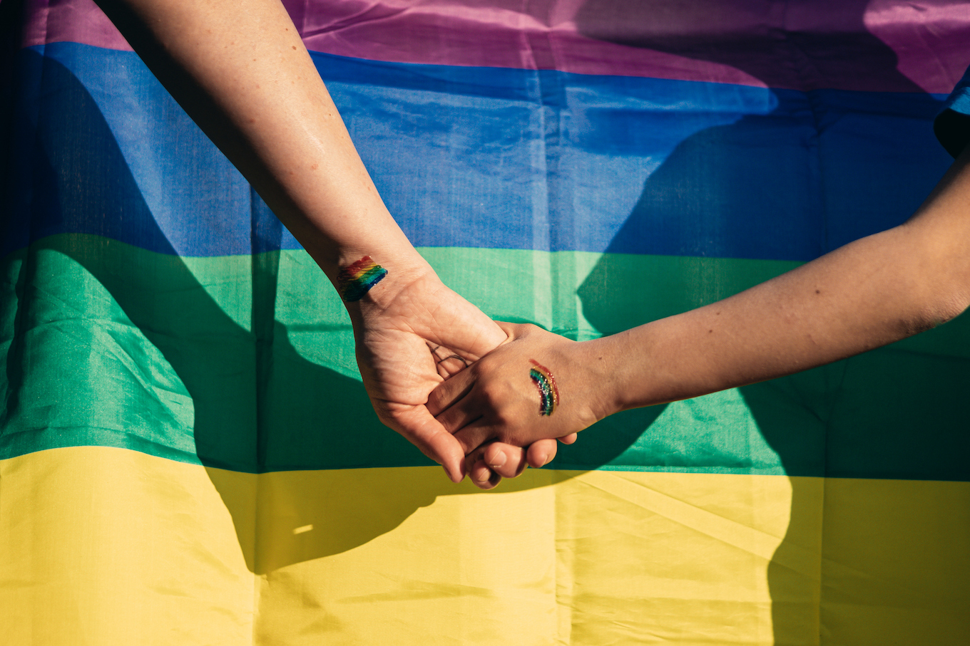 holding hands in front of pride flag