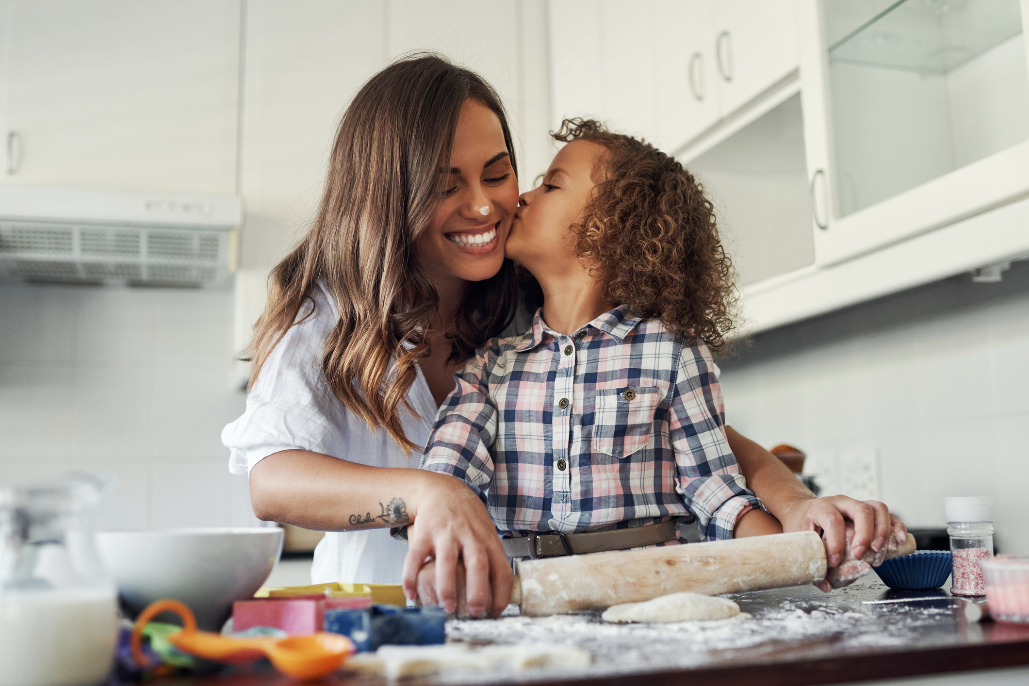Shot of an adorable little girl being affectionate while baking with her mom at home