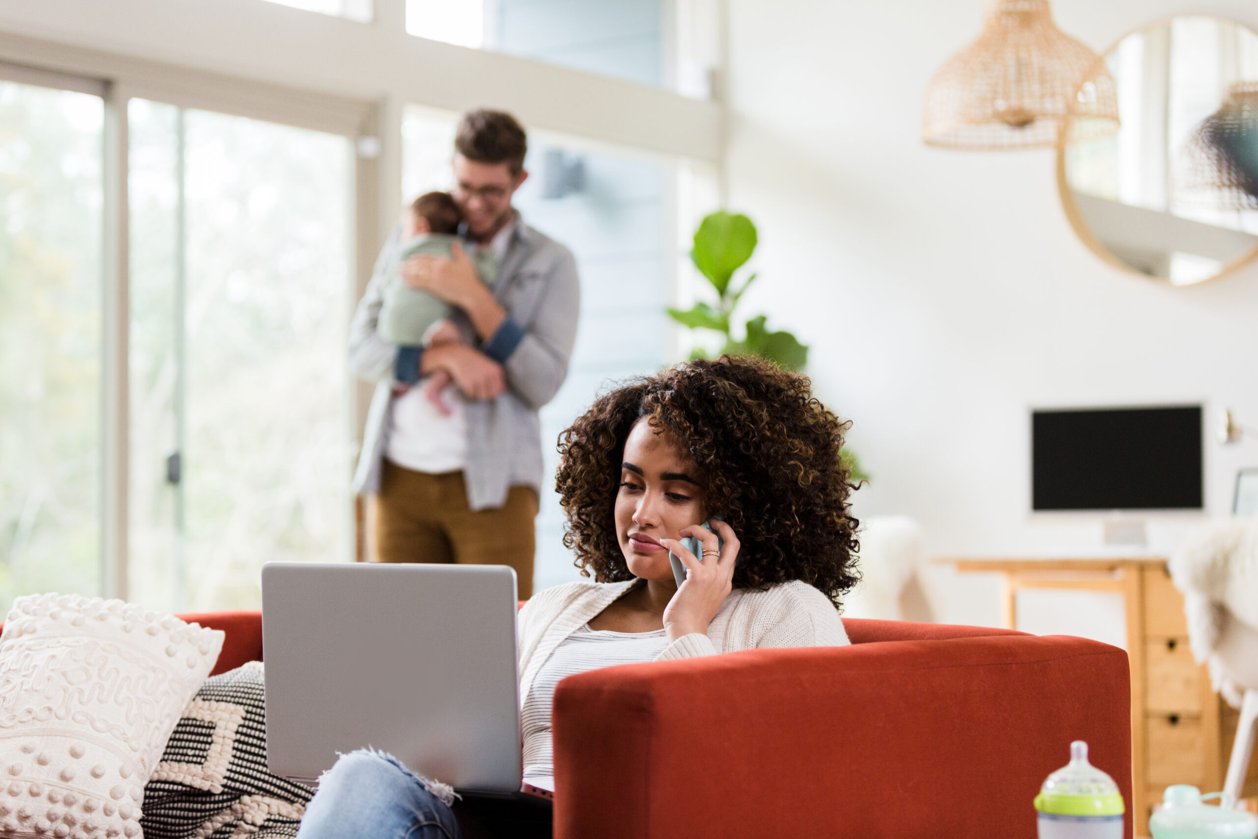 Working mom uses laptop as husband cares for baby
